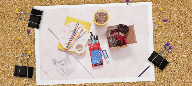 photo of a sketch book, palette, pencils and mug of coffee clipped to a notice board